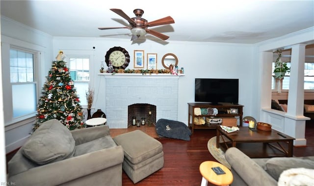 living room featuring a brick fireplace, crown molding, dark hardwood / wood-style floors, and ceiling fan