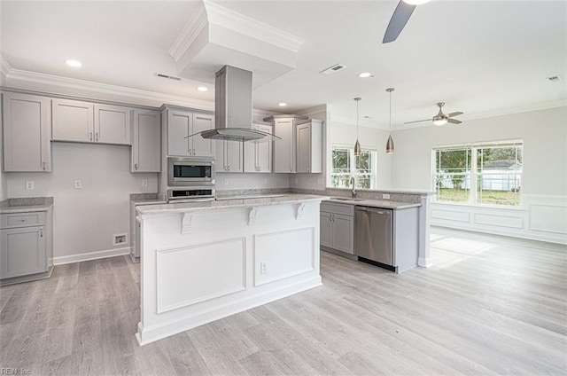 kitchen featuring island exhaust hood, ceiling fan, appliances with stainless steel finishes, gray cabinetry, and a kitchen island