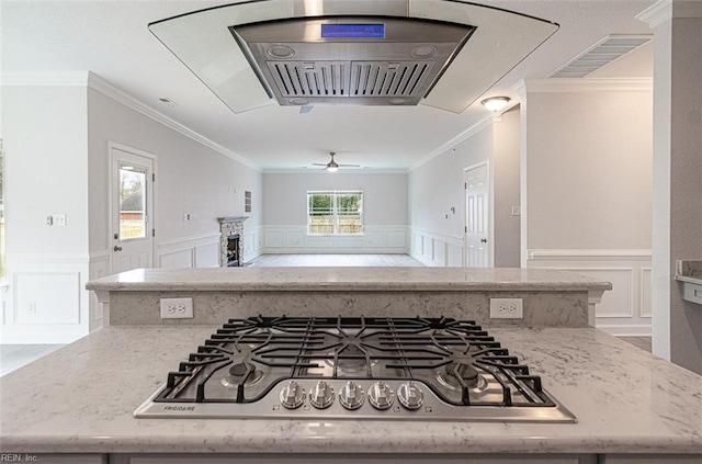 kitchen featuring ceiling fan, light stone countertops, stainless steel gas stovetop, and crown molding