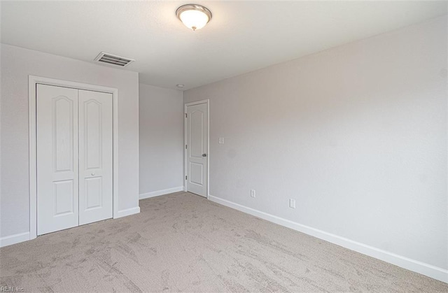 unfurnished bedroom featuring a closet and light colored carpet