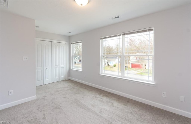 unfurnished bedroom featuring a closet and light carpet