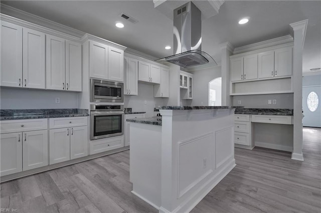 kitchen with light wood-type flooring, appliances with stainless steel finishes, island range hood, and white cabinets