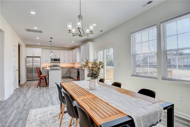 dining area with a notable chandelier, light hardwood / wood-style floors, and sink