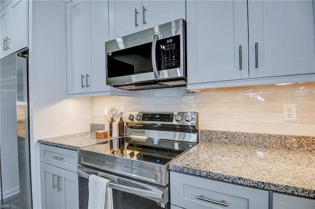 kitchen with backsplash, light stone counters, and stainless steel appliances