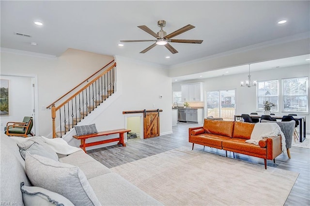 living room with ceiling fan with notable chandelier, crown molding, and light hardwood / wood-style floors