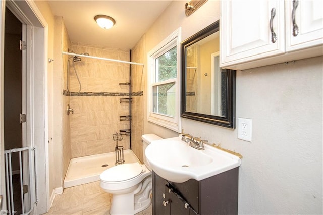 bathroom with toilet, tile patterned floors, tiled shower, and vanity