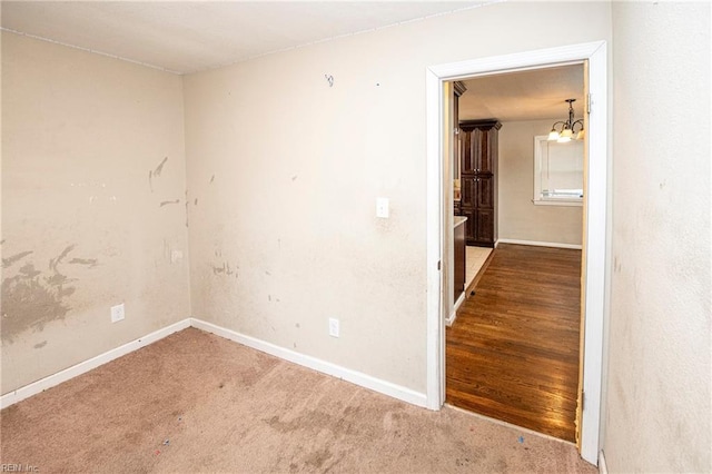 carpeted spare room featuring a notable chandelier