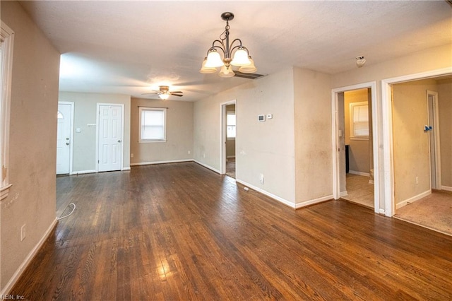 empty room featuring dark hardwood / wood-style flooring and ceiling fan with notable chandelier