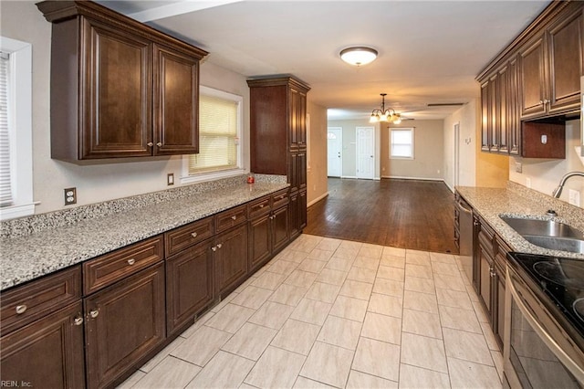 kitchen featuring appliances with stainless steel finishes, light stone countertops, sink, and a chandelier