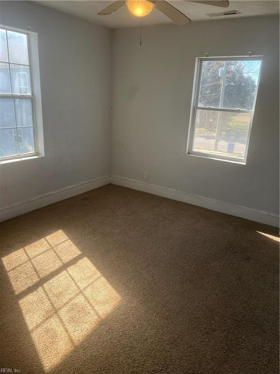 spare room with carpet, visible vents, ceiling fan, and baseboards