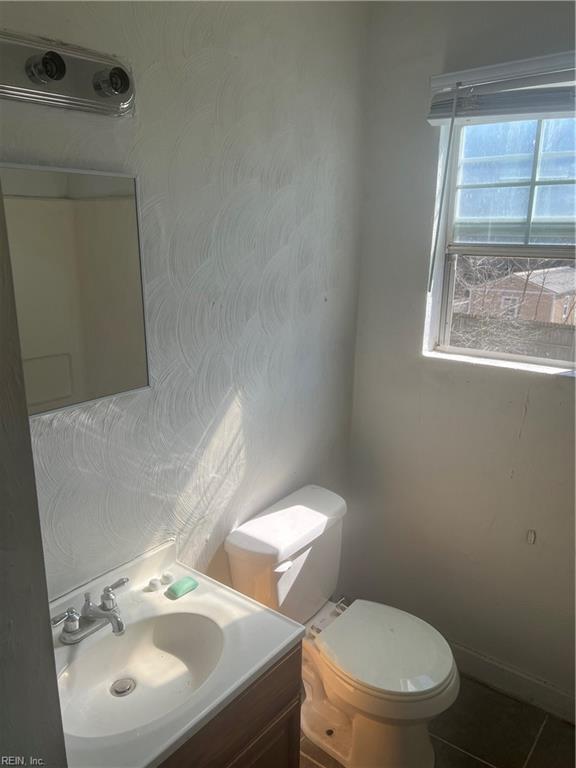 half bathroom with vanity, toilet, and tile patterned floors