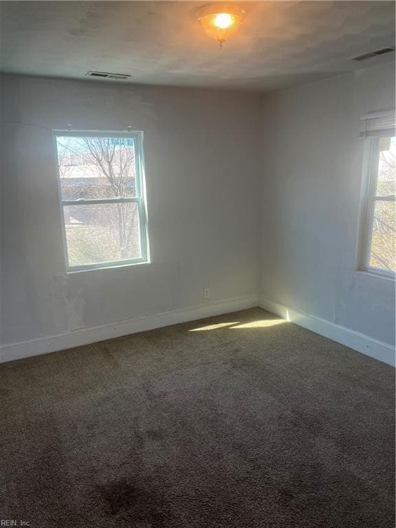 unfurnished room with carpet, visible vents, and baseboards