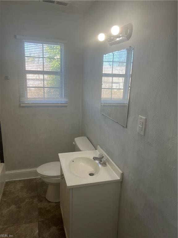 full bath with baseboards, plenty of natural light, vanity, and toilet