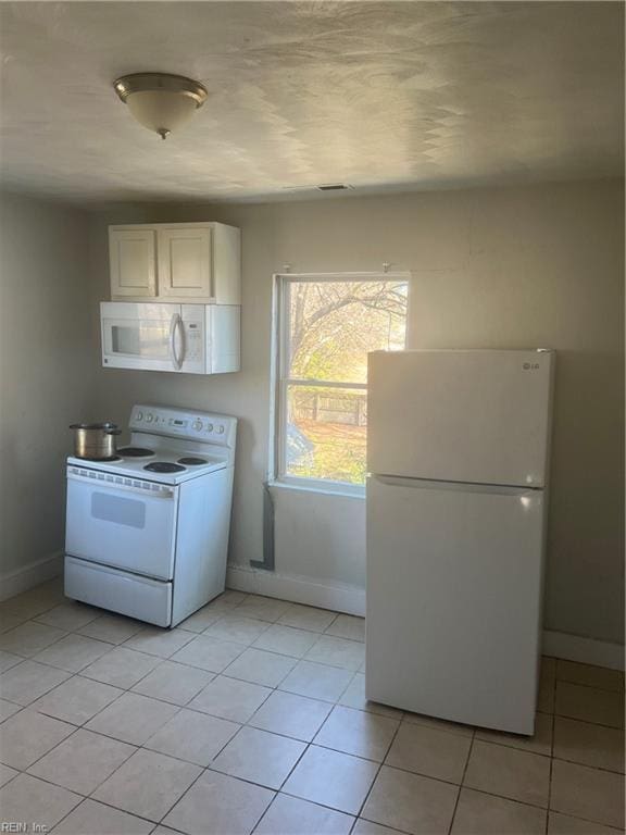 kitchen featuring white appliances, white cabinetry, baseboards, and light tile patterned floors