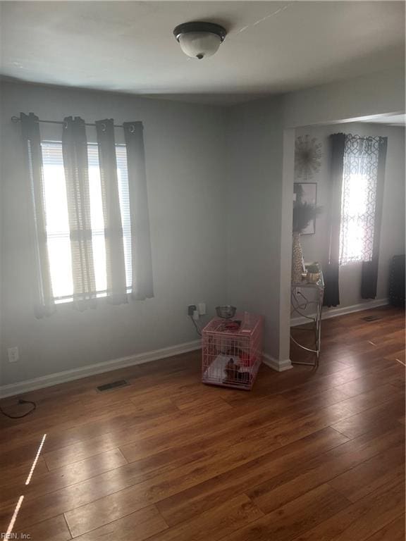 empty room featuring baseboards, visible vents, and hardwood / wood-style floors