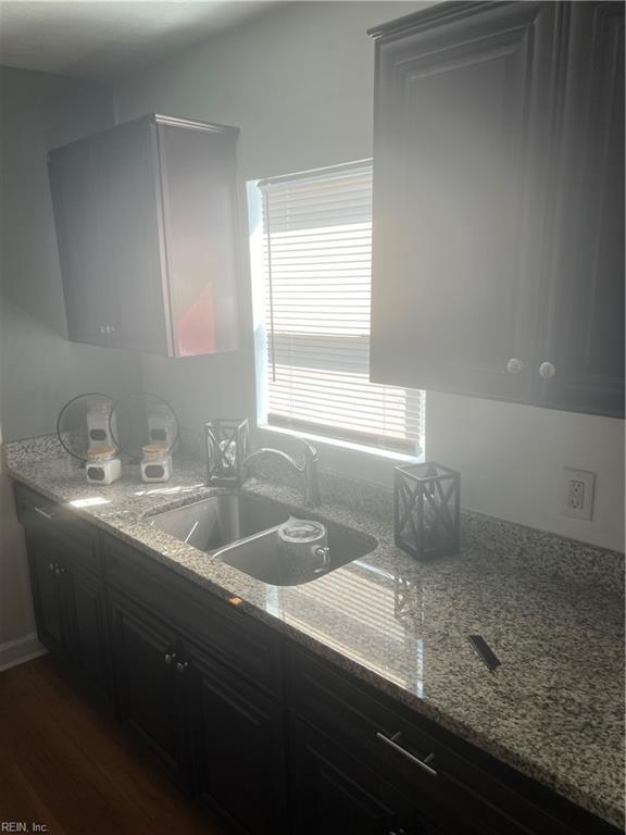 kitchen featuring dark wood-style flooring, a sink, and light stone countertops