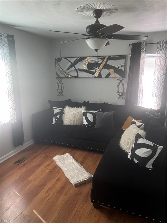 interior space featuring a ceiling fan, baseboards, visible vents, and wood finished floors