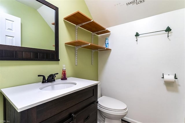 bathroom featuring toilet, vanity, and lofted ceiling