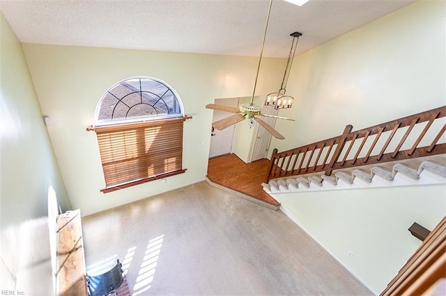 foyer with ceiling fan with notable chandelier, plenty of natural light, a textured ceiling, and lofted ceiling