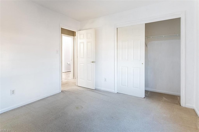 unfurnished bedroom featuring light carpet and a closet