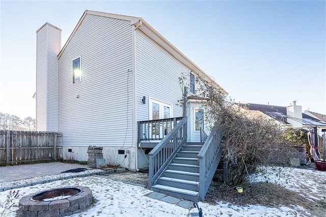 view of snow covered exterior featuring a wooden deck and a fire pit