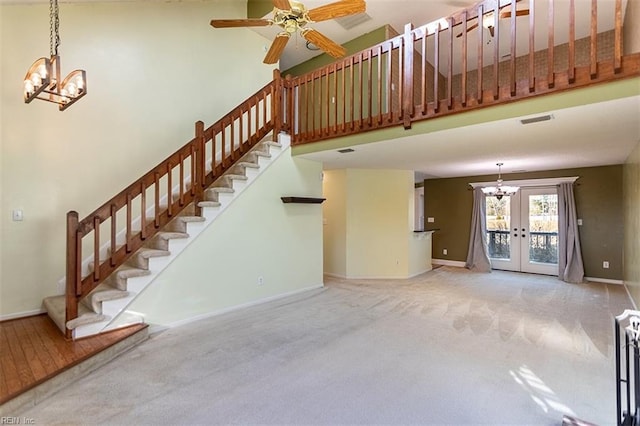 unfurnished living room featuring carpet, french doors, and ceiling fan with notable chandelier