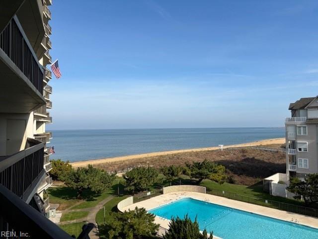 view of swimming pool with a water view and a view of the beach