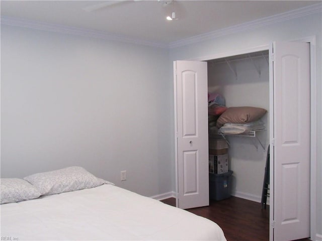 bedroom featuring ceiling fan, a closet, dark wood-type flooring, and crown molding