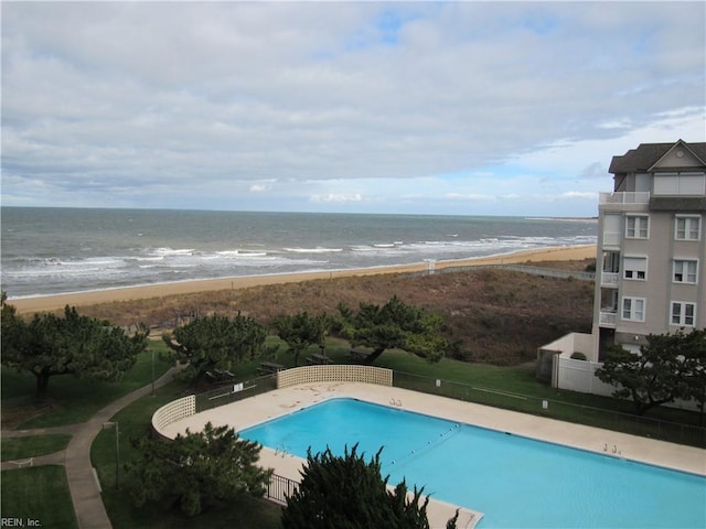 view of swimming pool featuring a beach view, a patio area, and a water view