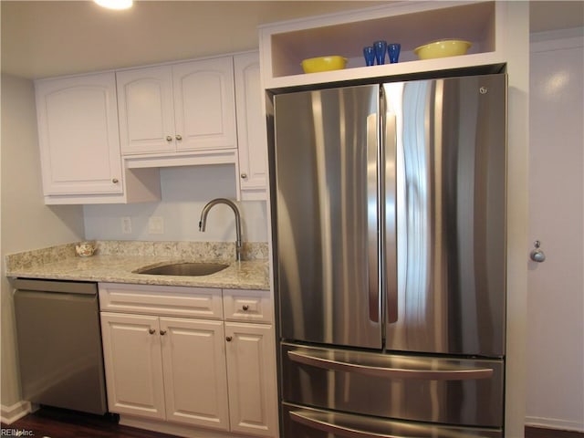 kitchen with sink, white cabinetry, light stone countertops, appliances with stainless steel finishes, and dark hardwood / wood-style flooring