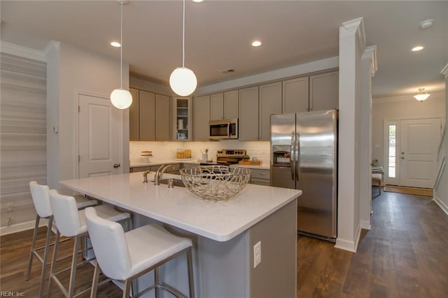 kitchen featuring a center island with sink, appliances with stainless steel finishes, backsplash, dark hardwood / wood-style flooring, and hanging light fixtures