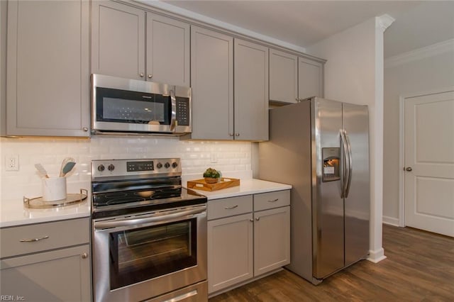 kitchen featuring backsplash, crown molding, dark wood-type flooring, gray cabinetry, and stainless steel appliances