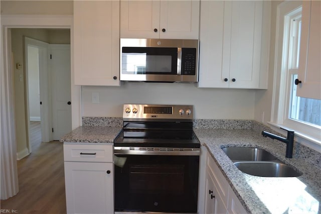 kitchen with sink, stainless steel appliances, white cabinets, and light stone countertops