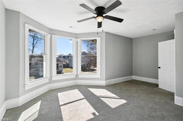 empty room featuring ceiling fan and dark carpet