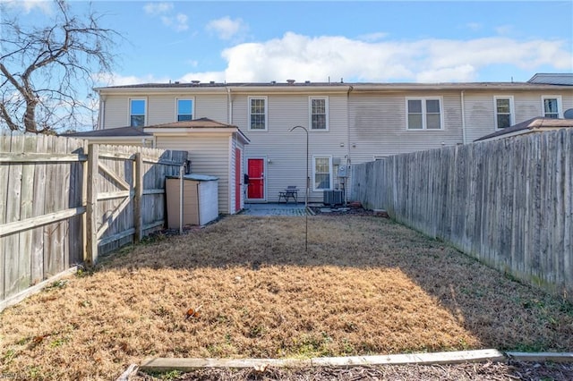 back of house with cooling unit, a patio area, and a lawn