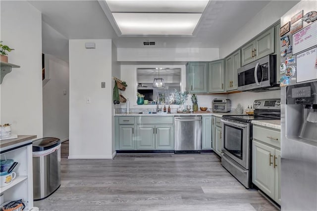 kitchen featuring sink, decorative light fixtures, stainless steel appliances, and light hardwood / wood-style floors