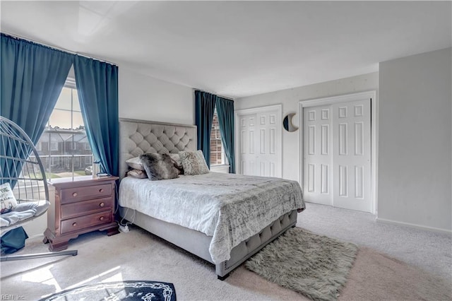 bedroom featuring two closets and light colored carpet