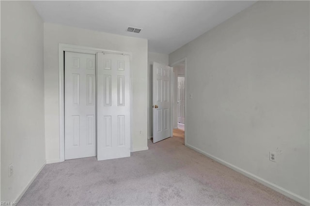 unfurnished bedroom featuring a closet and light carpet