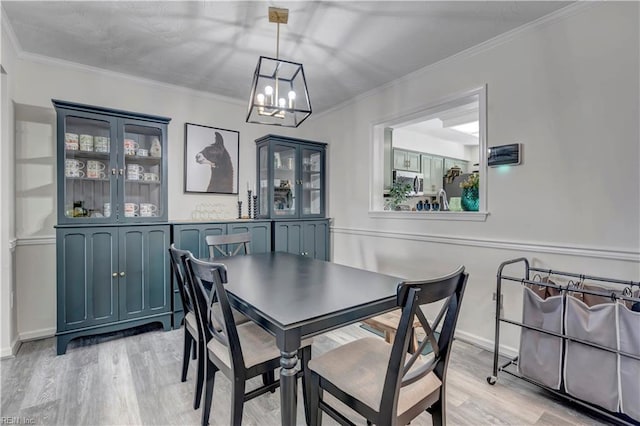 dining room with ornamental molding, a chandelier, and light hardwood / wood-style flooring