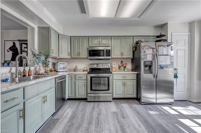 kitchen with stainless steel appliances, sink, and light hardwood / wood-style flooring