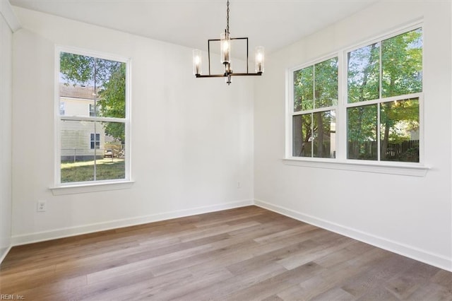 unfurnished dining area with light hardwood / wood-style floors and a notable chandelier