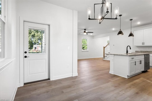 kitchen with dishwasher, sink, white cabinetry, and a center island with sink