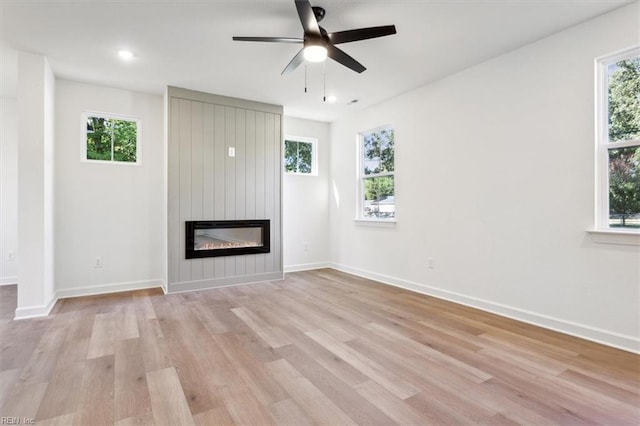 unfurnished living room featuring light hardwood / wood-style floors, a large fireplace, and ceiling fan