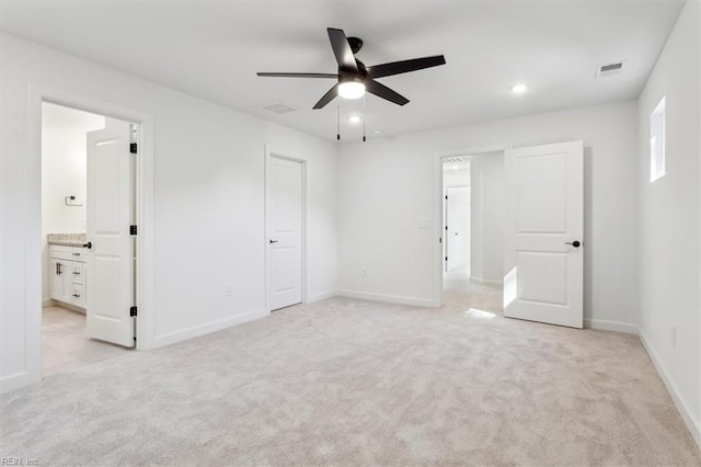 unfurnished bedroom featuring ceiling fan, light colored carpet, and connected bathroom