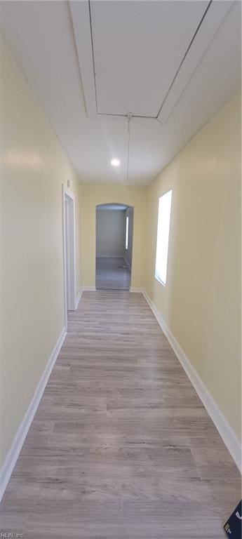 corridor featuring attic access, baseboards, and wood finished floors