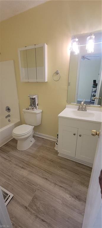 bathroom with toilet, vanity, wood finished floors, and visible vents