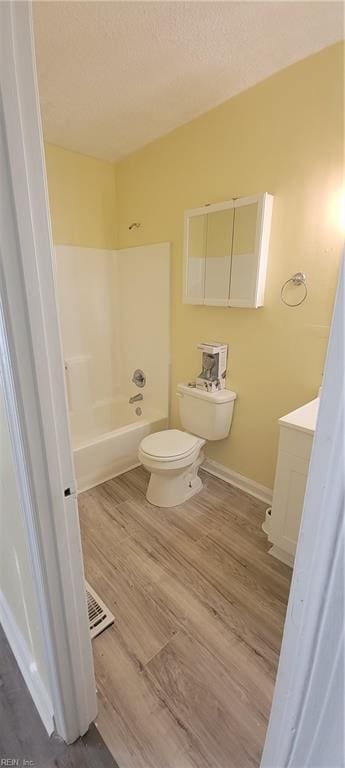 bathroom featuring toilet, a textured ceiling, wood finished floors, and vanity