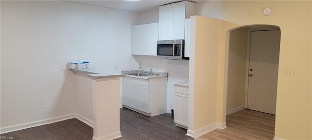 kitchen with dark wood-style floors, light countertops, stainless steel microwave, and a sink