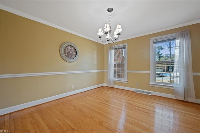 spare room with a notable chandelier, crown molding, and light hardwood / wood-style floors