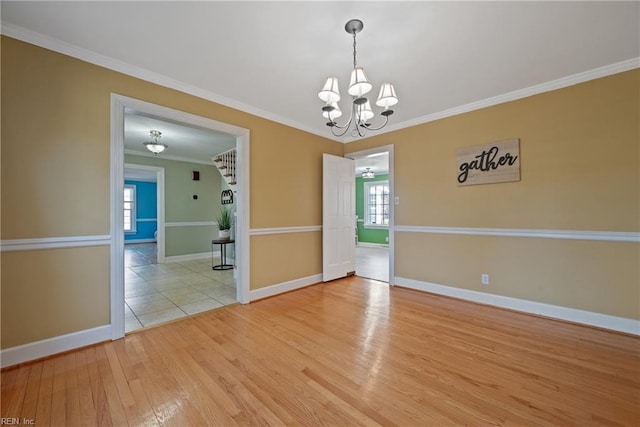 unfurnished room with light hardwood / wood-style floors, plenty of natural light, ornamental molding, and a notable chandelier